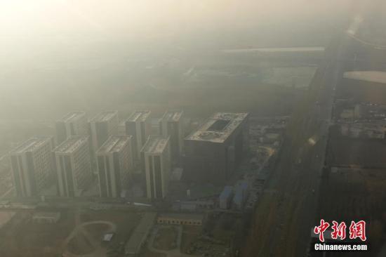 　　12月16日,，透過飛機舷窗俯瞰北京,，城市建筑隱在霧霾中。12月15日北京發(fā)布今年首個空氣重污染紅色預警：16日20時,，北京市啟動空氣重污染紅色預警,。中新社記者 盛佳鵬 攝